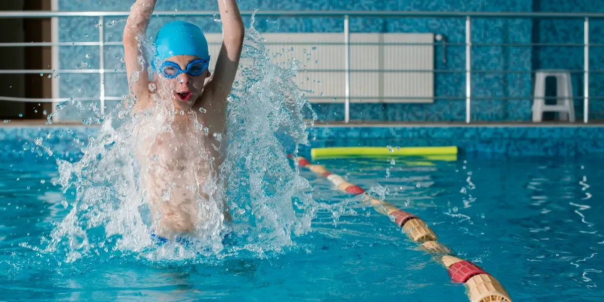 Child swimming freestyle with goggles in pool
